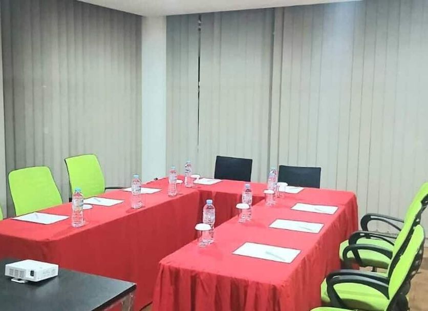 Hotel Cikini Jakarta meeting room with U-shaped table, red tablecloths and lime green chairs