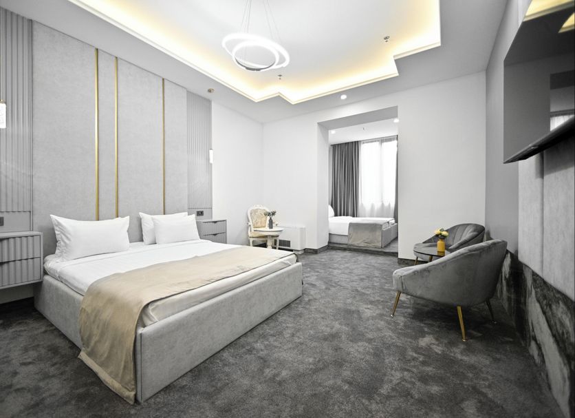 Imperial Palace Hotel Yerevan guest room with king bed, sitting area and gray carpet