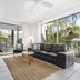 Metzo Noosa Resort in Noosa Heads living room with sofa, rug and patio doors to a tropical terrace