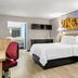 Days Inn by Wyndham Salina South guest room with king bed, sofa, desk, and bathroom view in Salina