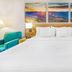 Days Inn Roanoke Near I-81 guest room with king bed, teal chair, and mountain artwork