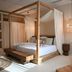 Umm Al Quwain Beach Hotel in Umm Al Qaiwain: four-poster bed with sheer canopy and wooden bench
