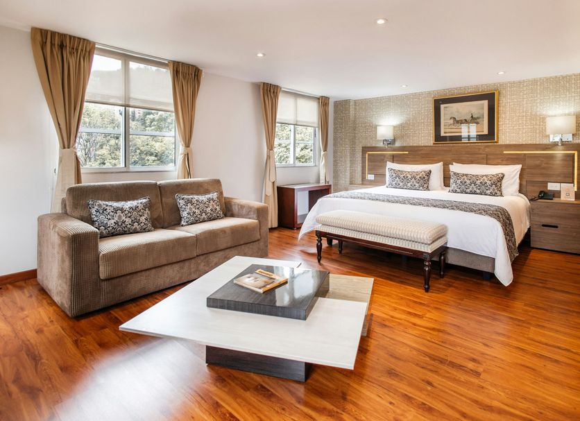 Hotel Porton De La Cabrera in Bogotá with king bed, sofa, coffee table and wood floors in a bright suite