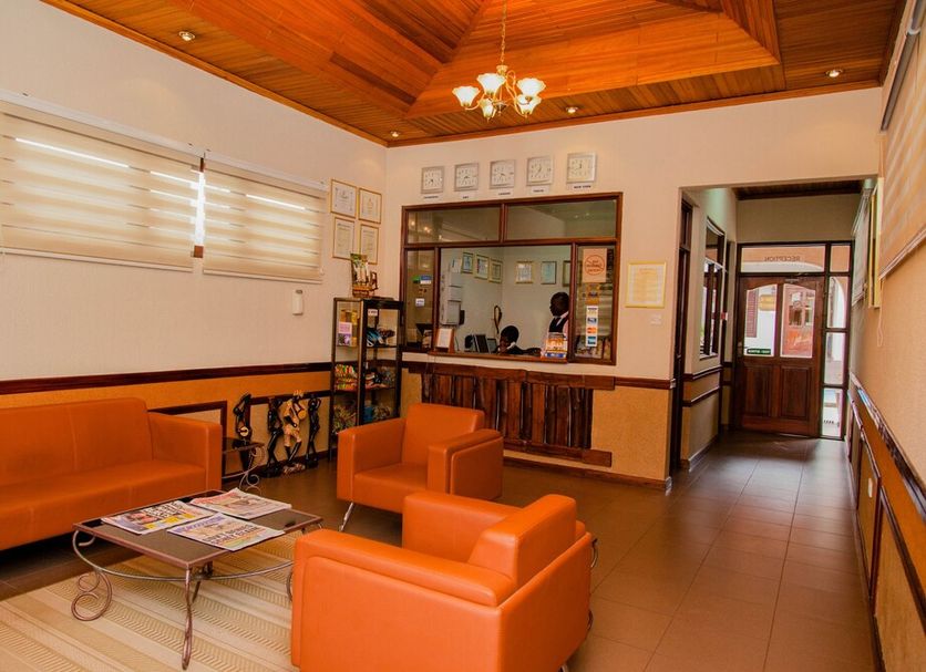 Mahogany Lodge, Accra lobby with orange seating, reception desk, wood-paneled ceiling and hallway