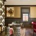 Zelda Dearest Asheville lounge with patterned chairs, floral arrangement, and dark wood paneling