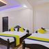 Hilltown Hotel in Madikeri guest room with two beds, purple ceiling lights, and red curtains