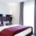 Fair Hotel Europaallee in Frankfurt am Main guest room with double bed, purple headboard and curtains
