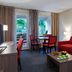 Residence La Reserve Ferney-Voltaire room with red sofa, table, desk and balcony doors