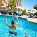 Hampton Inn Pensacola Beach pool scene with a man splashing in a sunny outdoor pool