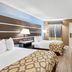 Baymont by Wyndham Forest City guest room with two beds, wall-mounted TV, and mini-fridge in Forest City