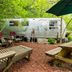 Country Woods Inn in Glen Rose: vintage silver trailer, picnic tables and lounge chairs under trees