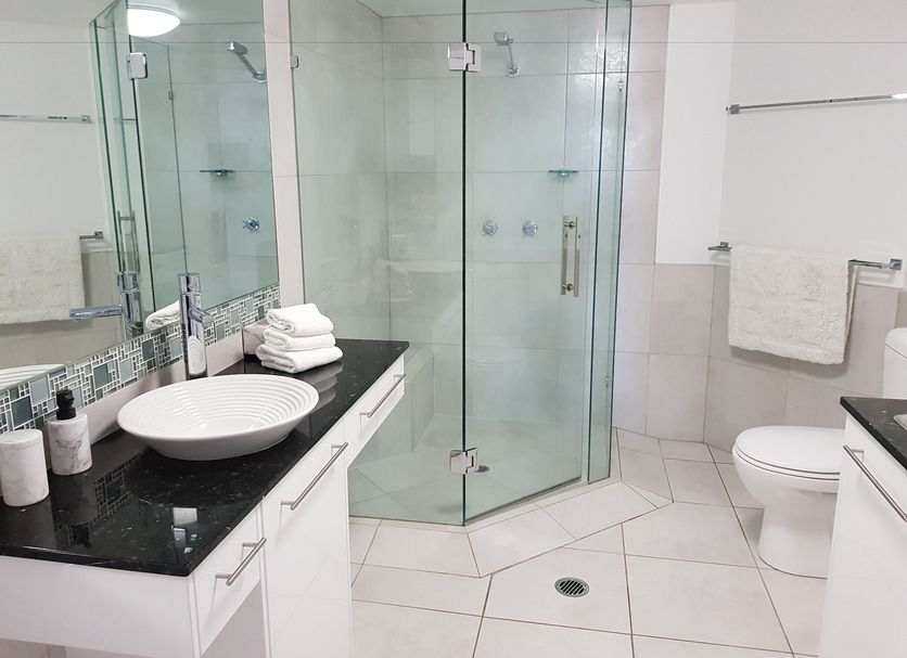 Excellsior Apartments Mooloolaba bathroom with glass shower, vessel sink and black vanity top