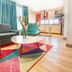Hotel Plaza Suites Bogotá living room with gray sofa, round table, teal chair and kitchen area