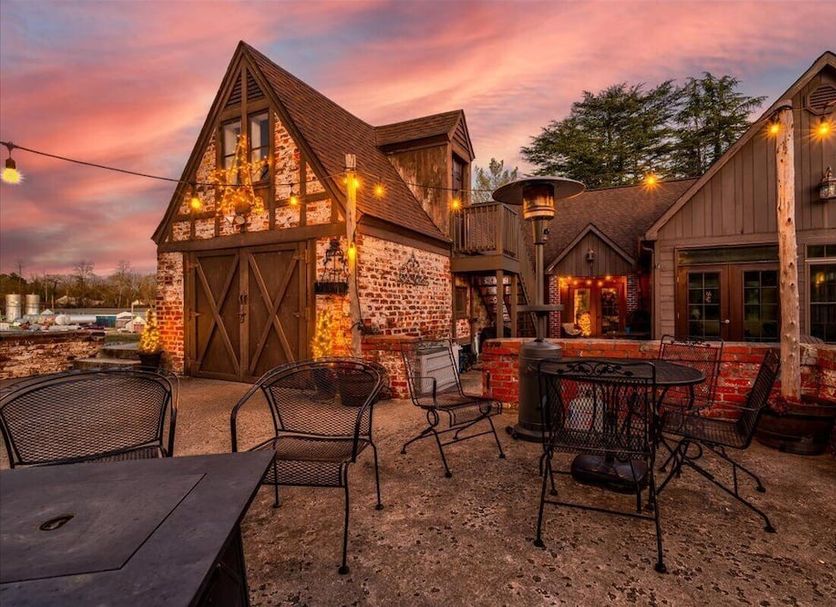 Longacre Of Appomattox outdoor patio with string lights, fire pit seating and rustic building at sunset