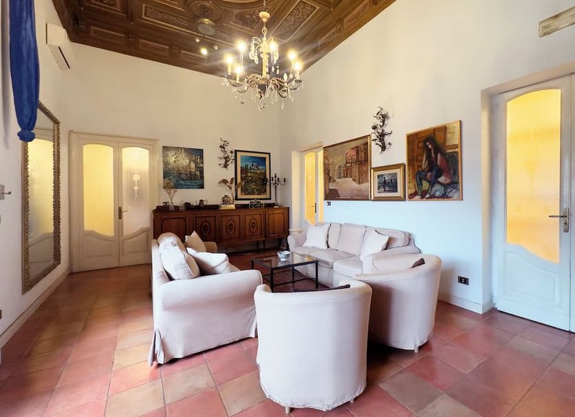 Antica Dimora Caruso in Catania: elegant sitting room with white sofas, chandelier and ornate ceiling