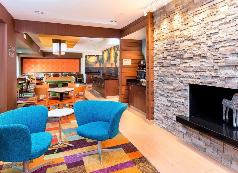 Fairfield Inn & Suites by Marriott Galesburg lobby with blue chairs, stone fireplace and colorful rug