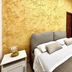 La Corte degli Spada - Borgo Antico del Salento bedroom with double bed and textured gold wall in Mesagne