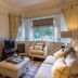 Crossbasket Castle in Glasgow living room with fireplace, sofa, armchair, and window view