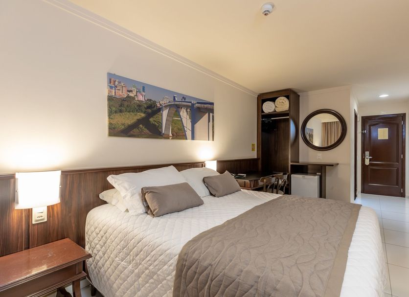 Bogari Hotel in Foz do Iguaçu guest room with king bed, wall art, desk and hallway view