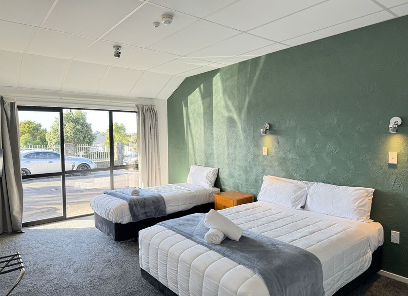 Oakwood Manor Motor Lodge in Mangere room with two beds, green wall and sliding glass door