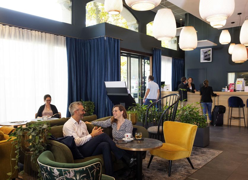 Aparthotel Adagio Lyon Patio Confluence lounge with seating area, bar, and large hanging lights in Lyon