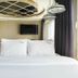 Jk Hotel Busan guest room with bed, wall-mounted TV, and large window with curtains