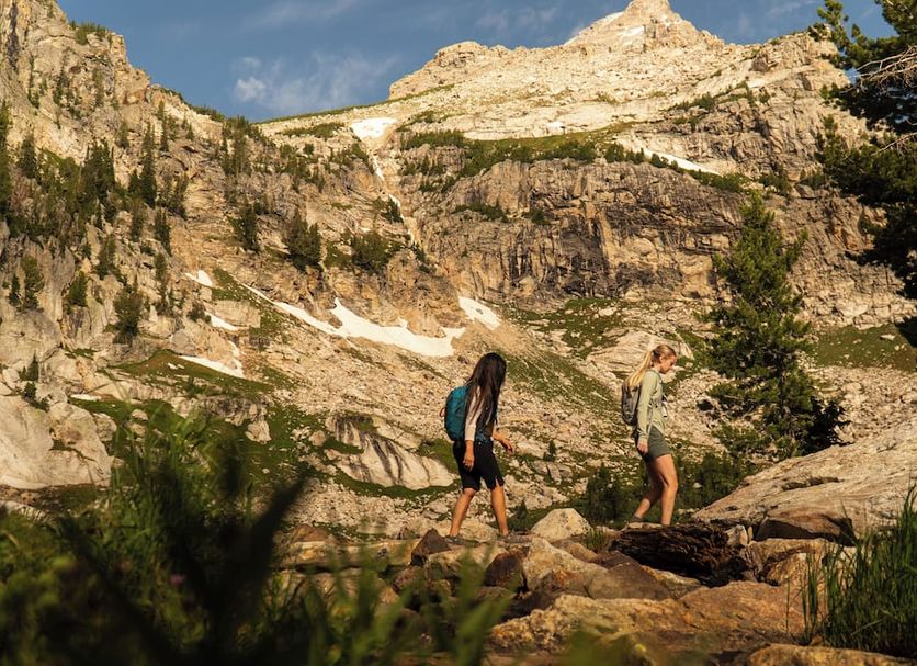 Huff House Inn and Cabins in Jackson with hikers on a rocky mountain trail and alpine cliffs