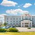 Hampton Inn Junction City exterior with parking lot, landscaped shrubs, and a partly cloudy sky