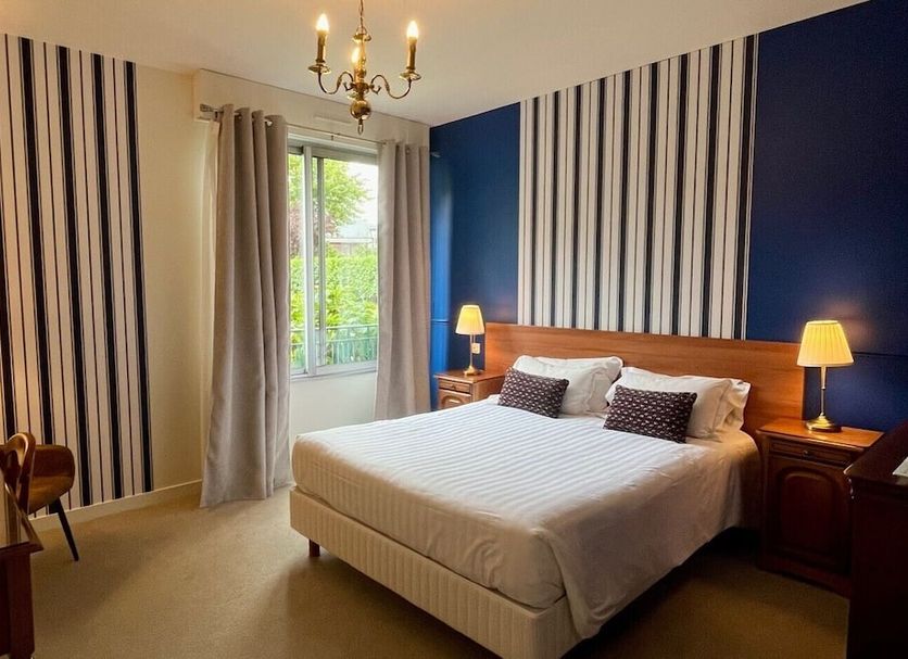 Hôtel de la Marine in Saint-Herblain bedroom with striped wallpaper, double bed, and window view