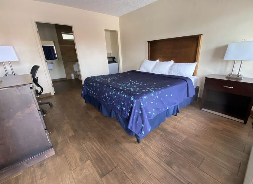 Coral Roc Motel in Florida City guest room with king bed, desk, lamps and wood-look tile floor