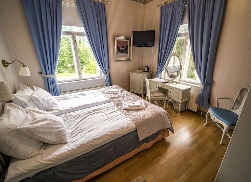 Karolineburg Manor House Hotel in Kajaani guest room with twin bed, vanity desk, and blue curtains