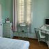 La Villa Des Violettes in Toulouse guest room with bed, desk, chair, window shutters and mint green walls