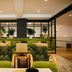 Emeline in Charleston lobby lounge with green banquettes, patterned chairs and warm ceiling lights