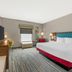 Hampton Inn Junction City guest room with king bed, wall-mounted TV, and window seat