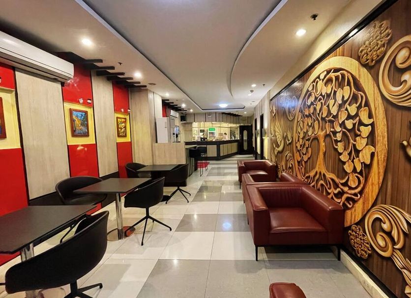 Hotel 99 Cubao Manila lobby seating area with ornate wood wall art and tables