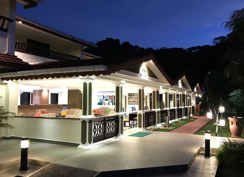 Berjaya Praslin Resort in Baie Sainte Anne, lit resort exterior with walkway at dusk