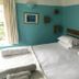 The White House in Bishop's Stortford guest room with a bed, teal walls, framed art and window
