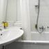Ibis Styles Riga bathroom with bathtub, shower, sink and towel rack