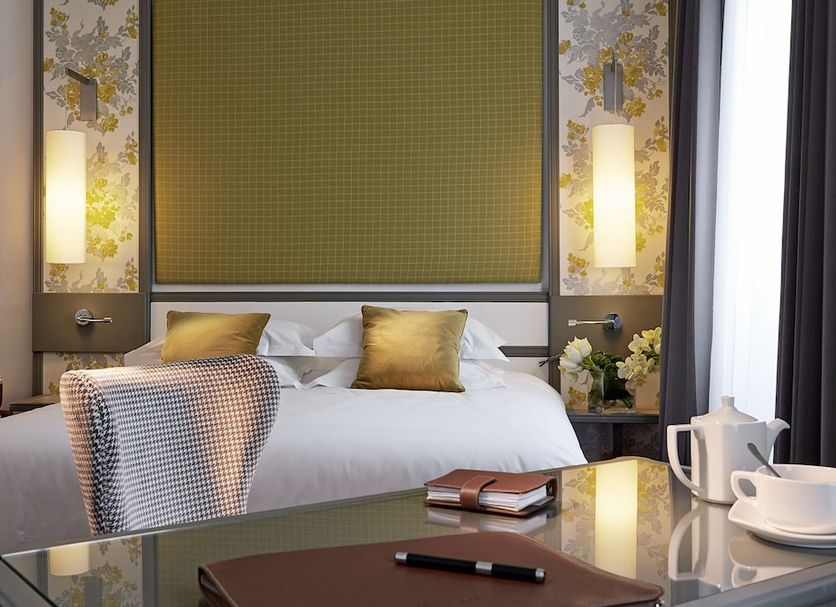 Hotel America Cannes guest room with king bed, bedside lamps and desk by a window