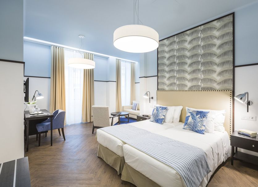 Castanheiro Boutique Hotel Funchal guest room with king bed, desk, tall windows and modern lighting