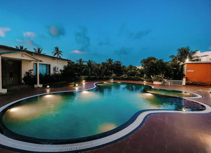 Chanakya Bnr Hotel in Puri with a lit outdoor swimming pool at dusk