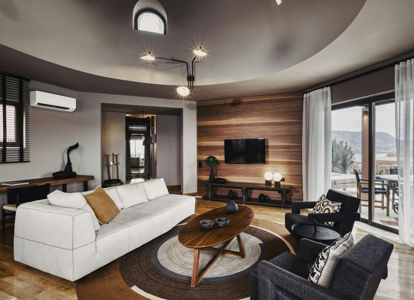 Domes of Elounda, Autograph Collection living room with sofa, TV, balcony and sea view in Elounda