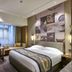 Henan Sky-Land Gdh Hotel in Zhengzhou guest room with king bed, sofa seating, and city-view window