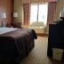 Baymont by Wyndham Midland Airport room with king bed, two lamps, and window with curtains in Midland