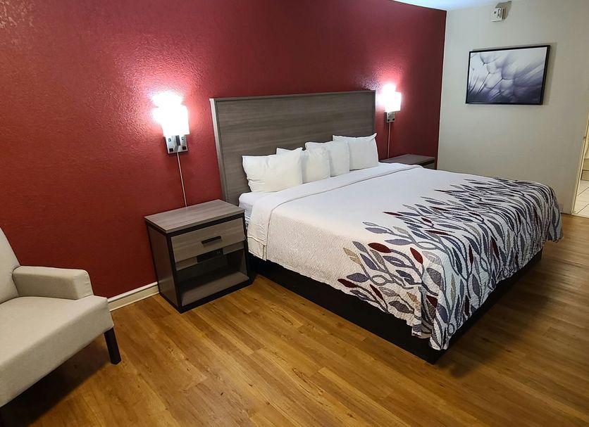 Red Roof Inn & Suites Cornelius - Lake Norman room with king bed, red accent wall, and chair