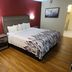 Red Roof Inn & Suites Cornelius - Lake Norman room with king bed, red accent wall, and chair
