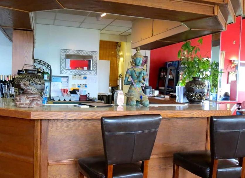 Budget Host Airport Inn in Waterville lobby bar with wooden counter, stools, and decorative plants