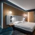 Artis Loft Hotel Mszczonów modern guest room with double bed, wood slat wall and teal chair