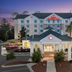 Hilton Garden Inn Tallahassee Central exterior at dusk with entrance, palm trees and pool area