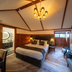 Hana Lodge in Hamurana bedroom with king bed, chandelier, and wood-paneled seating area